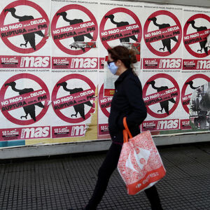 FILE PHOTO: A pedestrian wearing a protective face mask walks past posters on the street that read 'No to the payment of the debt. Break with the IMF', in Buenos Aires