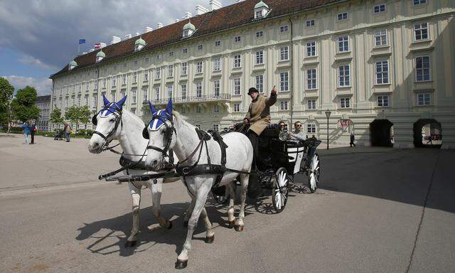 A traditional Fiaker horse carriage passes the Leopoldine Wing of Hofburg palace hosting the presidential office in Vienna