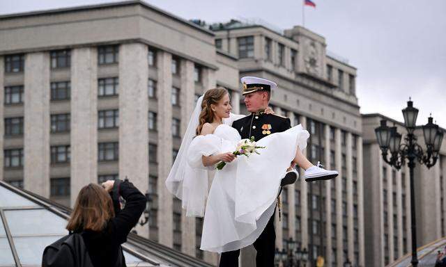 Ein frisch verheirtatetes Paar macht Fotos vor der Duma, dem russischen Parlament. Dort wurde ein Gesetz beschlossen, das einige Ehen in Russland beendet.