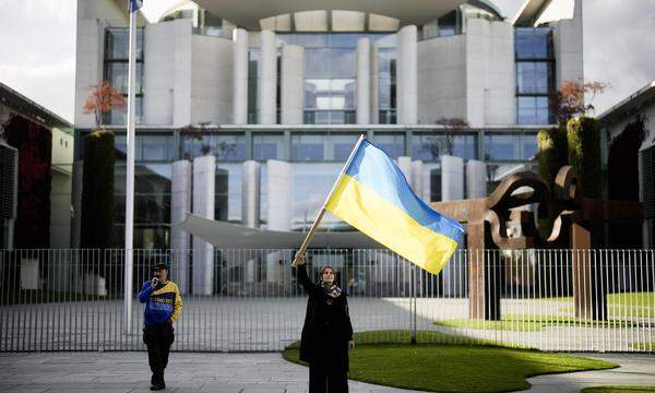 Vor dem deutschen Kanzleramt in Berlin schwingt eine Frau die ukrainische Fahne.