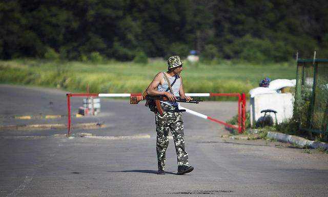 An armed pro-Russian separatist guards a border post abandoned by Ukrainian border guards at Chervonopartyzansk along the Ukraine-Russia border