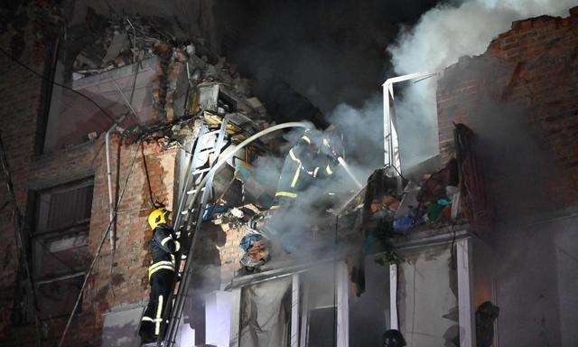 Feuerwehrmänner versuchen Personen aus einem attackierten Wohnhaus in Charkiw zu befreien.