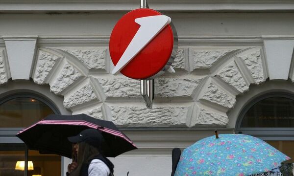 People carrying umbrellas pass a Bank Austria branch office in Vienna