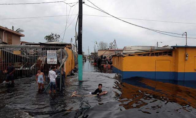 enjoy a moment in a flooded street after the area was hit by Hurricane Maria in Catano municipality, southwest of San Juan