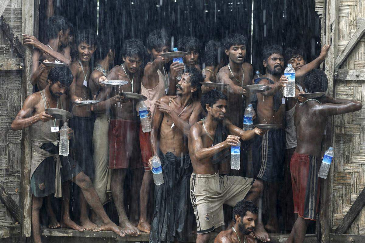 Migranten in einem Flüchtlingslager in Myanmar wollen ihre Wasserflaschen mithilfe des Regens füllen.