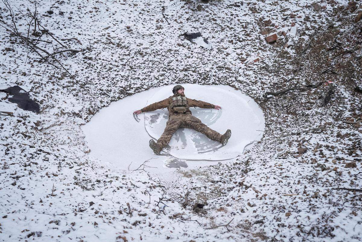 26. Jänner. Ein Engel mitten im Krieg - aus Schnee: Ein ukrainischer Soldat nahe Bachmut in der Region Donezk zeichnet Formen in den Schnee.   