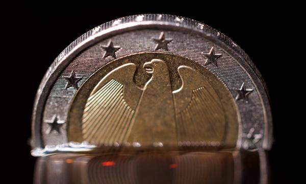 Eine Zwei-Euro-Münze taucht in eine Flüssigkeit ein. 