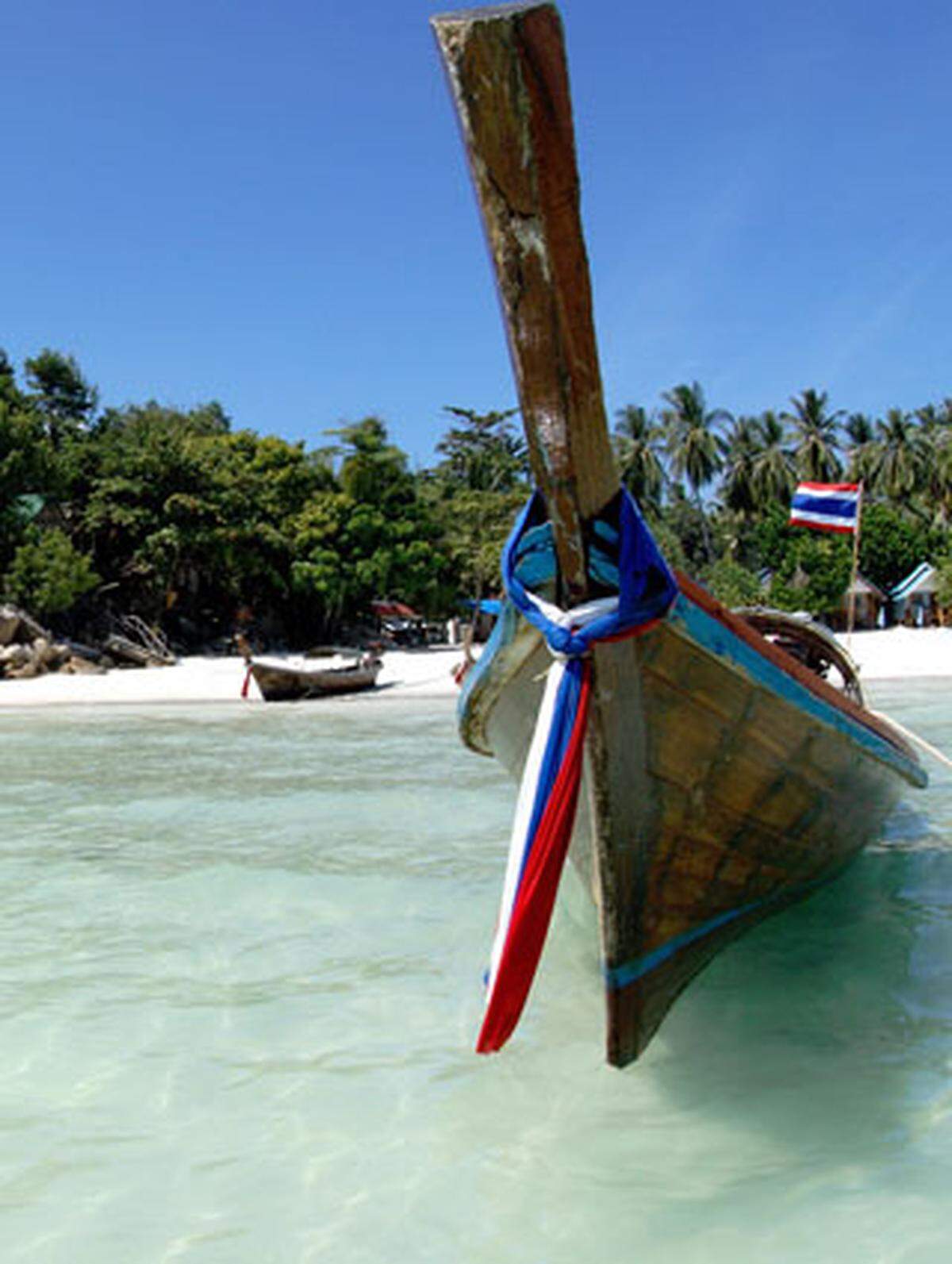 Am Strand der Insel Ko Lipe liegen auch die bekannten thailändischen Langboote vor Anker.