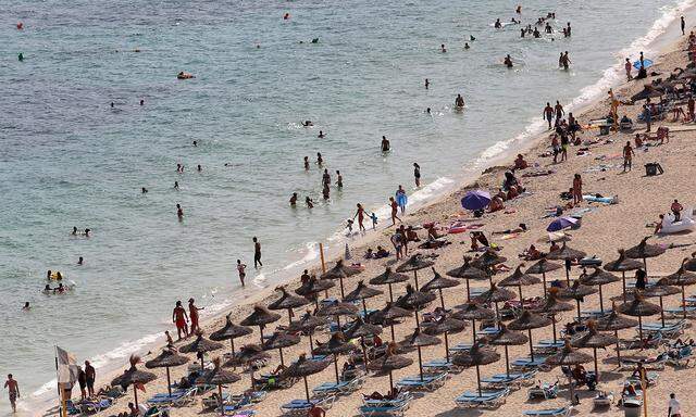 Tourists sunbathe and swim at the beach of Magaluf on the island of Mallorca