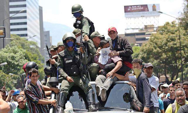 Soldiers ride on top of a car with supporters of Venezuelan opposition leader Juan Guaido during anti-goverment protests, in Caracas