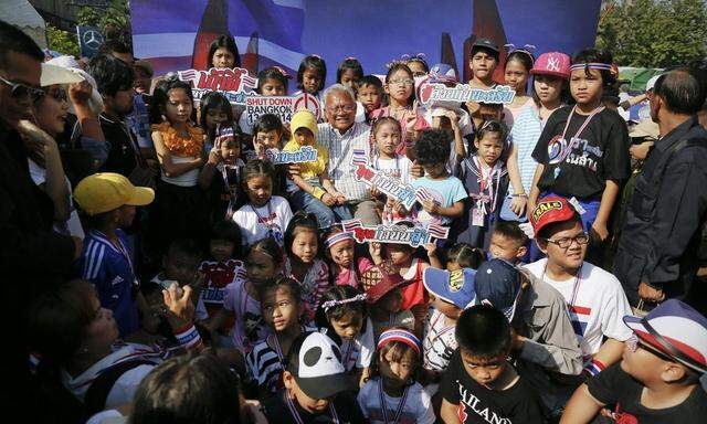 Protest leader Suthep Thaugsuban is surrounded by children as others take pictures inside the anti-government encampment in front of Democracy monument in Bangkok
