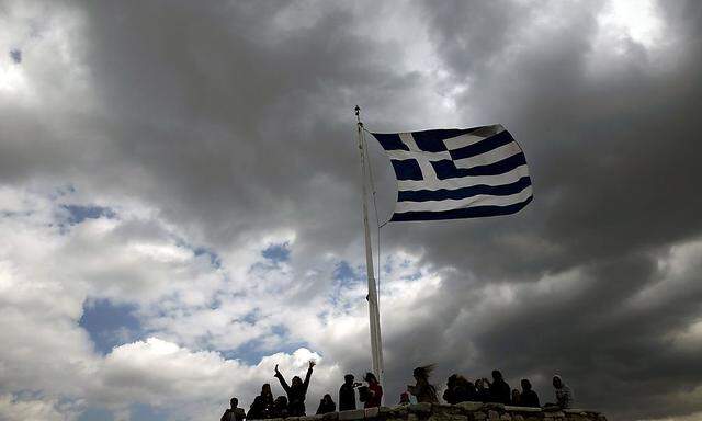 File photo of people silhouetted under a fluttering Greek national flag atop the archaeological site of the Athens Acropolis