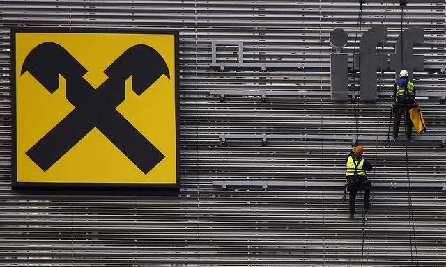 Workers are suspended as they assemble letters of the Raiffeisen Polbank's bank logo on their new building in Warsaw