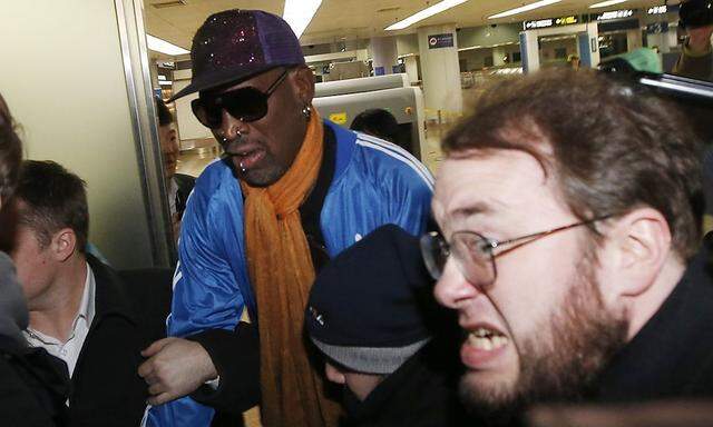 Bodyguards clear a path for Dennis Rodman as journalists surround him upon his arrival from North Korea's Pyongyang at Beijing Capital International Airport