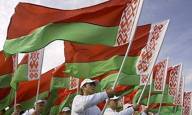 Young men hold Belarussian national flags during a harvest festival in the town of Orsha