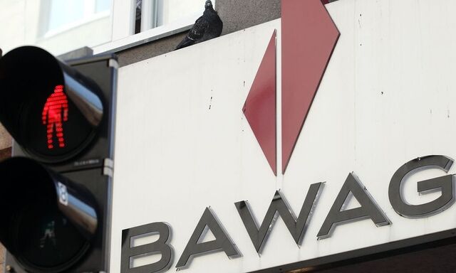 A pigeon sits atop the logo of Austrian lender BAWAG PSK next to traffic lights at a branch office in Vienna