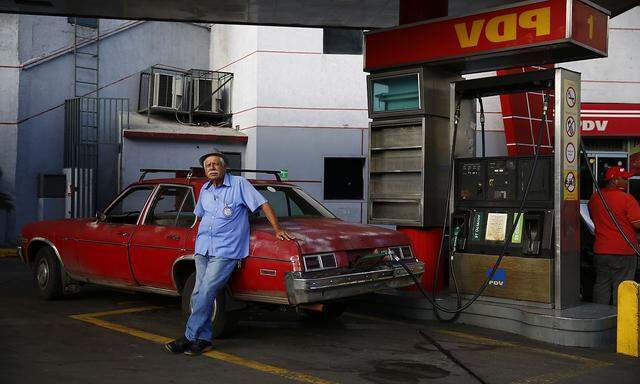 A man fills up his 1976 Chevy Nova with gasoline at a PDVSA gas station in Caracas