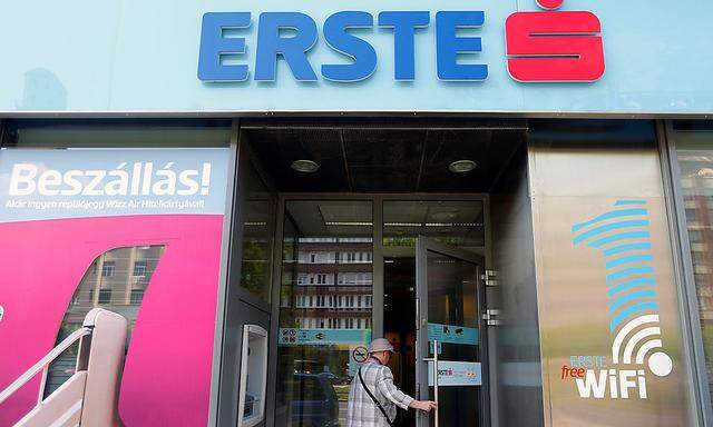 An elderly woman enters a branch office of Erste bank in Budapest
