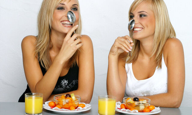 Blonde Zwillinge mit Obstsalat und Loeffel