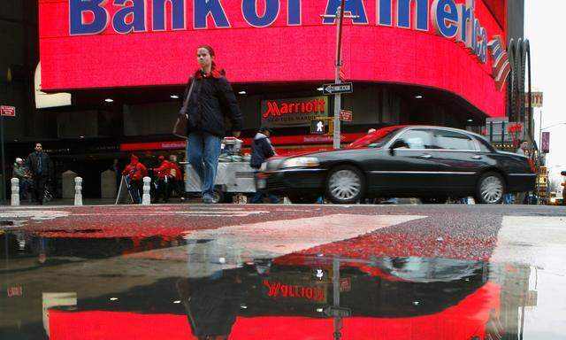 FILE PHOTO: FILE PHOTO: A woman is reflected in a puddle as she passes a Bank of America branch in New York's Times Square
