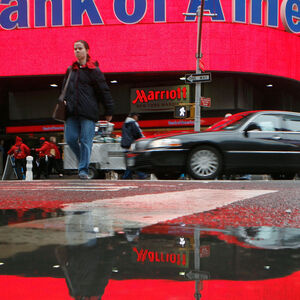 FILE PHOTO: FILE PHOTO: A woman is reflected in a puddle as she passes a Bank of America branch in New York's Times Square