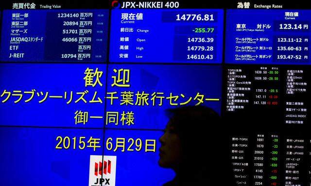 Woman stands in front of display showing market indices at Tokyo Stock Exchange in Tokyo