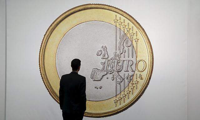 A man is silhouetted against 'SUPERFLEX, Euro 2012', a 416.6 cm by 289.6 cm (164 by 114 inch) large photographic print of an Euro coin on sale by the Los Angeles based gallery 1301 PE at the Art Cologne 2015 fair in Cologne