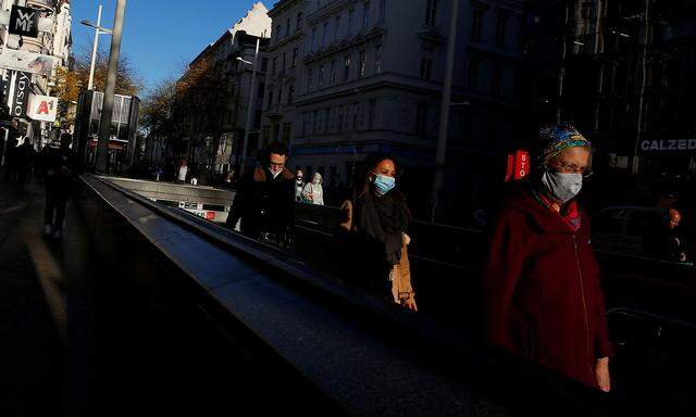 People wearing protective face mask exit a subway station in a pedestrian street in Vienna