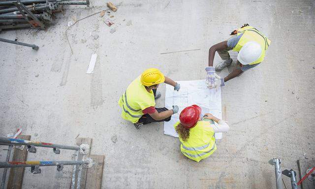 Architect reviewing blueprint with construction workers at building site Munich Bavaria Germany m