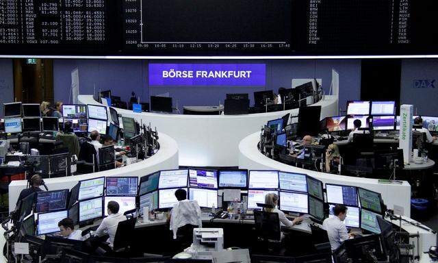 Traders work at their desks in front of the German share price index, DAX board, at the stock exchange in Frankfurt