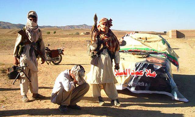Taliban fighters pose with weapons while detaining a man for campaigning for presidential candidate