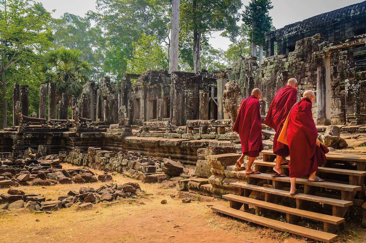 Buddhistische Mönche betreten einen Tempel in Angkor Wat: Es ist die bekannteste Tempelanlage in der Region Angkor in Kambodscha und repräsentiert den Berg Meru, Zentrum des Universums und Heimstatt der Hindu-Götter.