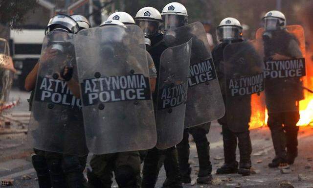 Riot police stand guard during clashes over stabbing of rapper in Athens