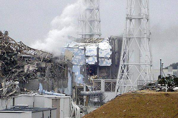 Am Mittwoch wurde das AKW Fukushima Eins noch von einer Pannenserie erschüttert. Im Bild: Weißer Rauch steigt aus dem Reaktor 3 (links vorn), in der Mitte Reaktor 4