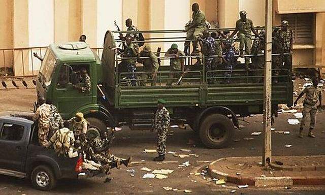 Malian soldiers and security forces gather at the offices of the state radio and television broadcast