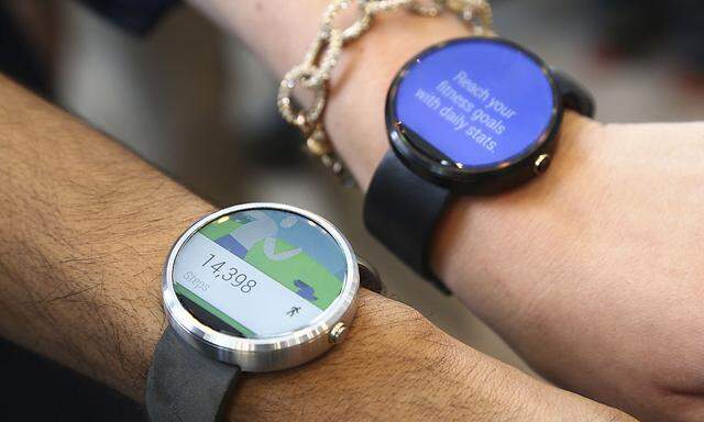 Google employees show off the two different colors of the Moto smartwatch at the Google I/O developers conference in San Francisco