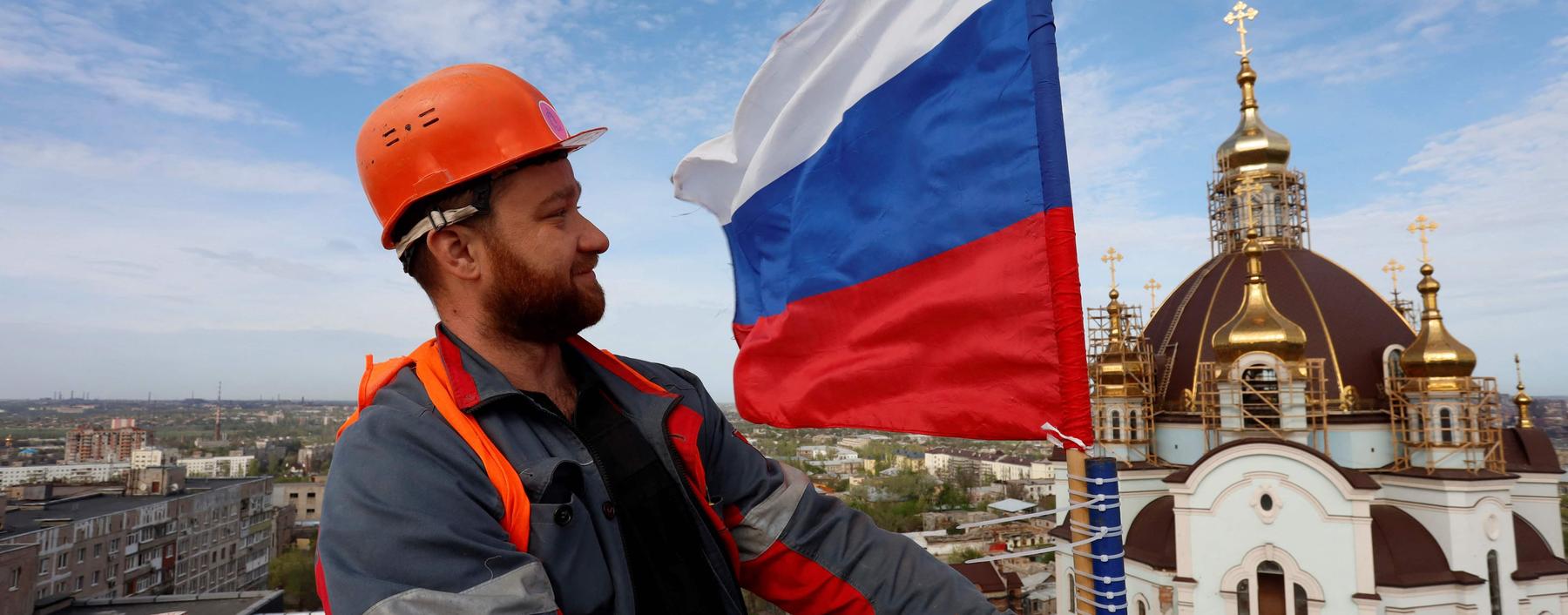 Wer macht sich der Hilfe für die Russen strafbar? Ein Bauarbeiter hisst eine russische Fahne auf dem Wasserturm in Mariupol. Die Stadt ist seit Mai 2022 unter russischer Kontrolle.