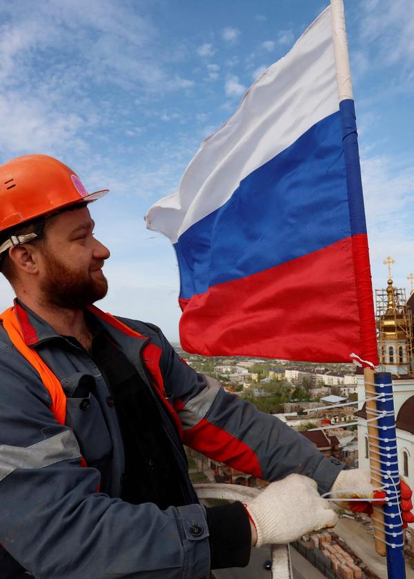 Wer macht sich der Hilfe für die Russen strafbar? Ein Bauarbeiter hisst eine russische Fahne auf dem Wasserturm in Mariupol. Die Stadt ist seit Mai 2022 unter russischer Kontrolle.