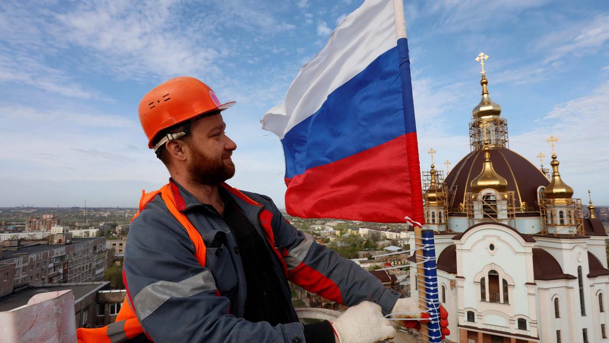 Wer macht sich der Hilfe für die Russen strafbar? Ein Bauarbeiter hisst eine russische Fahne auf dem Wasserturm in Mariupol. Die Stadt ist seit Mai 2022 unter russischer Kontrolle.