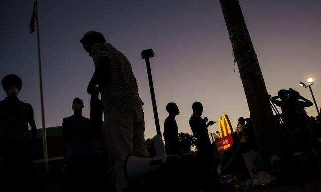 A small group of demonstrators stand in front of a McDonald's restaurant as they prepare to protest for another night in Ferguson, Missouri 