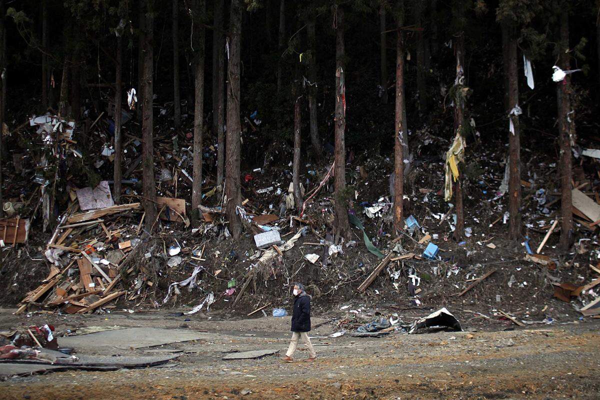 Mittwoch (23. März): Ein Mann passiert in der Präfektur Miyagi einen Trümmerhaufen, der vom Tsunami in den Wald gespült wurde.