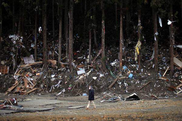 Mittwoch (23. März): Ein Mann passiert in der Präfektur Miyagi einen Trümmerhaufen, der vom Tsunami in den Wald gespült wurde.