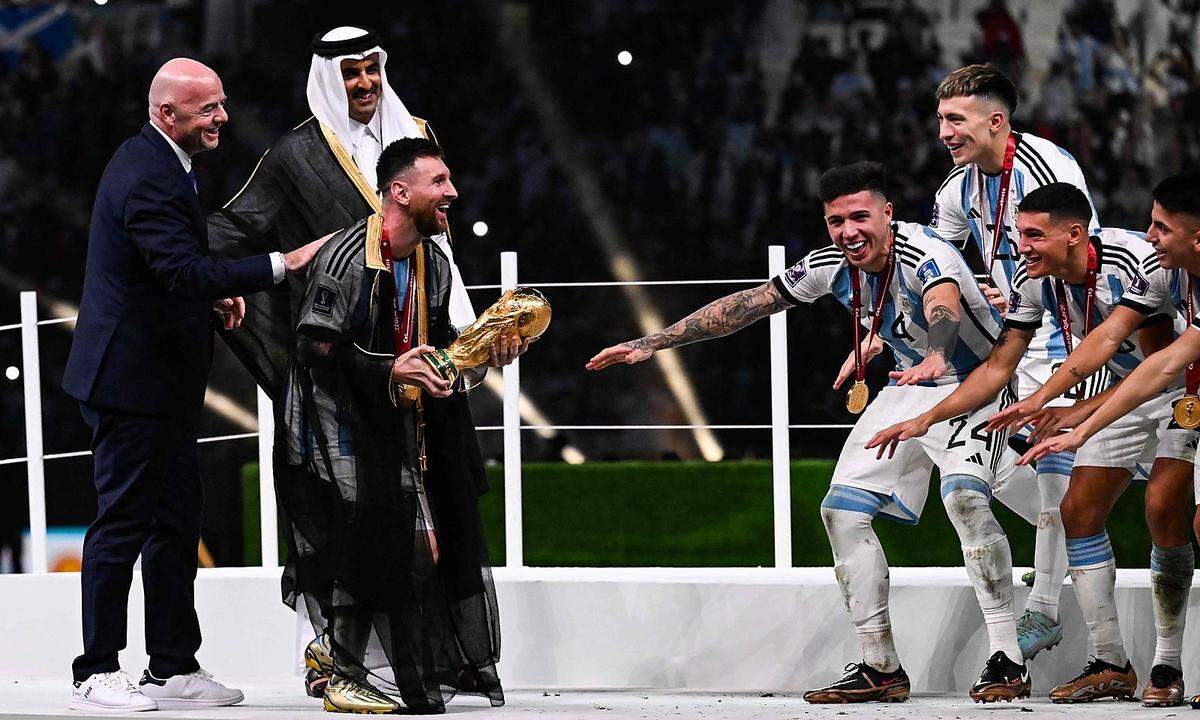 18. Dezember. Der argentinische Kapitän und Stürmer Lionel Messi hält den Fifa-Weltpokal neben Fifa-Präsident Gianni Infantino und dem Emir von Katar, Scheich Tamim bin Hamad al-Thani. Er feiert mit seinem Team und dem gesamten Land den Sieg im Finale der Fußballweltmeisterschaft Katar 2022 gegen Frankreich im Lusail-Stadion in Lusail.