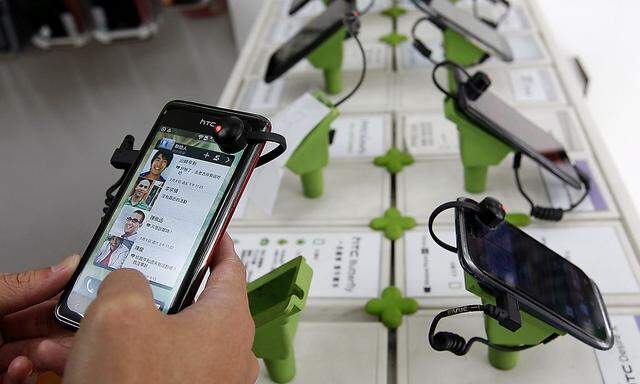 A customer plays with an HTC J smartphone in a mobile phone shop in Taipei