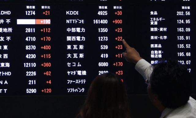 A visitor points at a stock price displayed on an electronic board at the Tokyo Stock Exchange in Tokyo