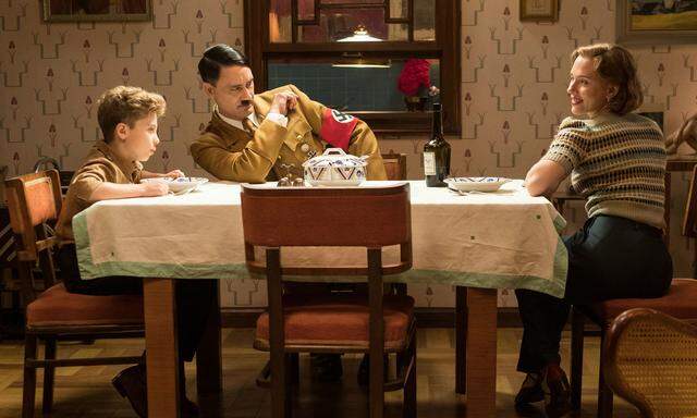Regisseur Taika Waititi als Jojos (li.) imaginärer Kumpel Hitler – am Tisch mit Jojos Mutter Rosie (Scarlett Johansson)