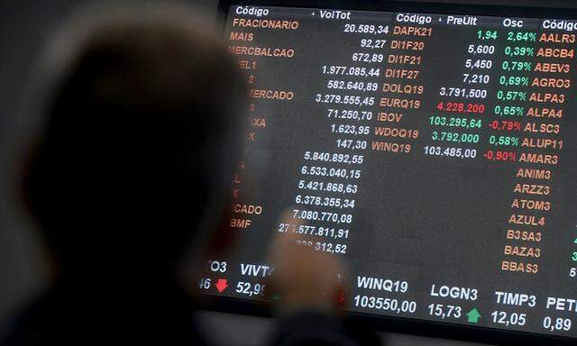 FILE PHOTO: Currency exchange rates of euro and the U.S. dollar are seen on an electronic board as a man points at it on the floor of Brazil's B3 Stock Exchange in Sao Paulo