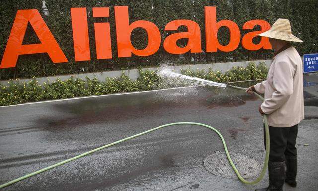 A cleaner waters the flowers below a logo of Alibaba (China) Technology Co. Ltd at the companyÂ´s headquarters on the outskirts of Hangzhou