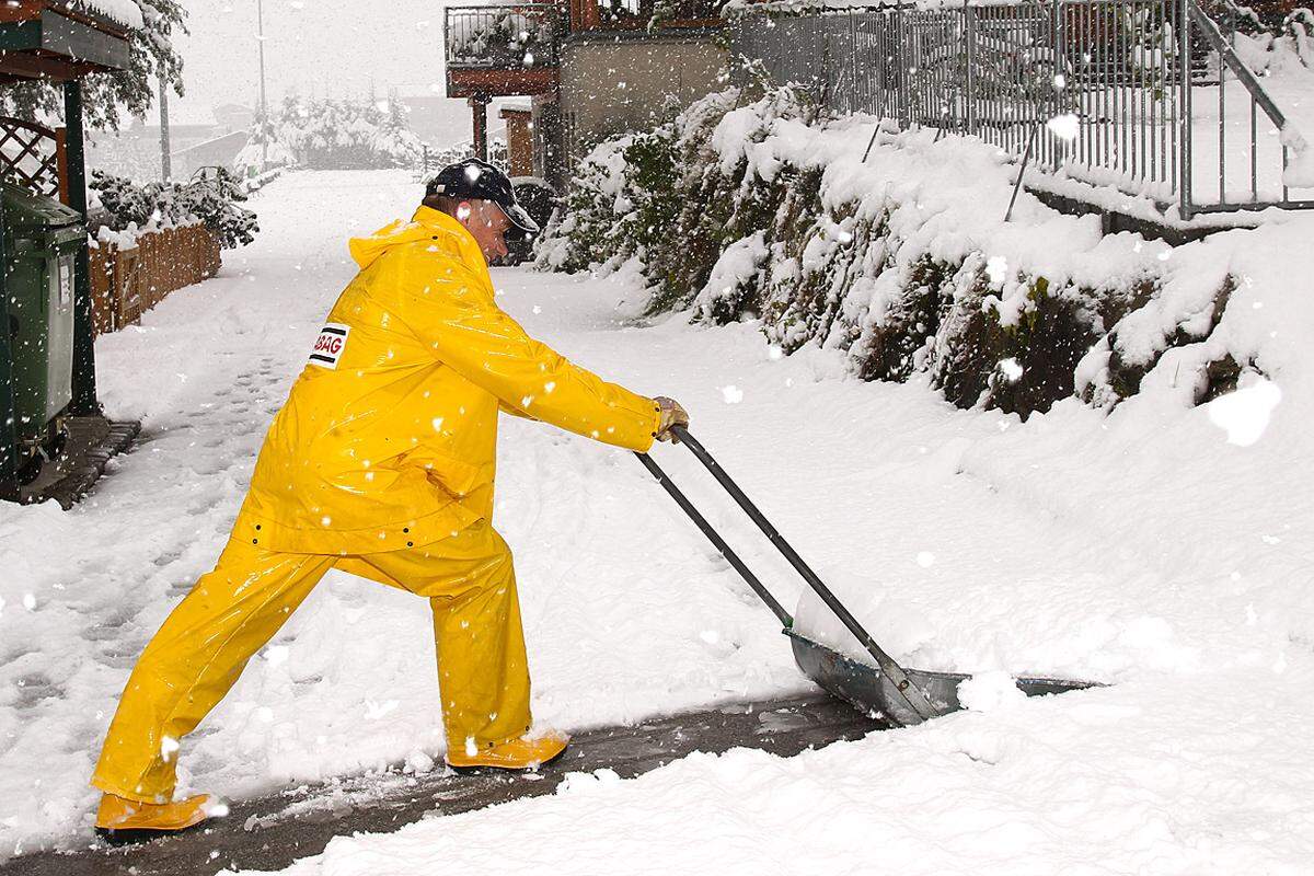 Im Bild: Ein Mann räumt einen Gehweg vom frisch gefallenen Schnee in Rauris, Salzburg.