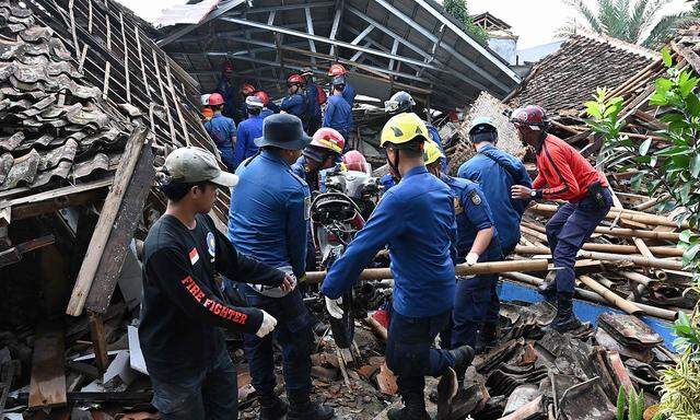 Rettungskräfte entfernen ein Motorrad, während sie nach einem vermissten Kind suchen, das in den Trümmern eines eingestürzten Hauses in Cugenang in Cianjur, Westjava, am 24. November verschüttet sein soll.
